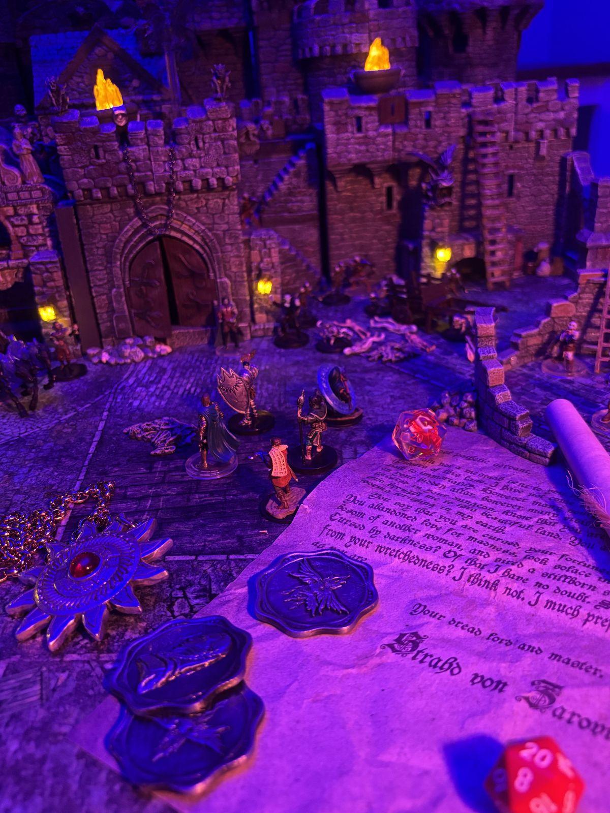 A real tabletop setup with adventurer miniatures confronting undead among illuminated modular ruins