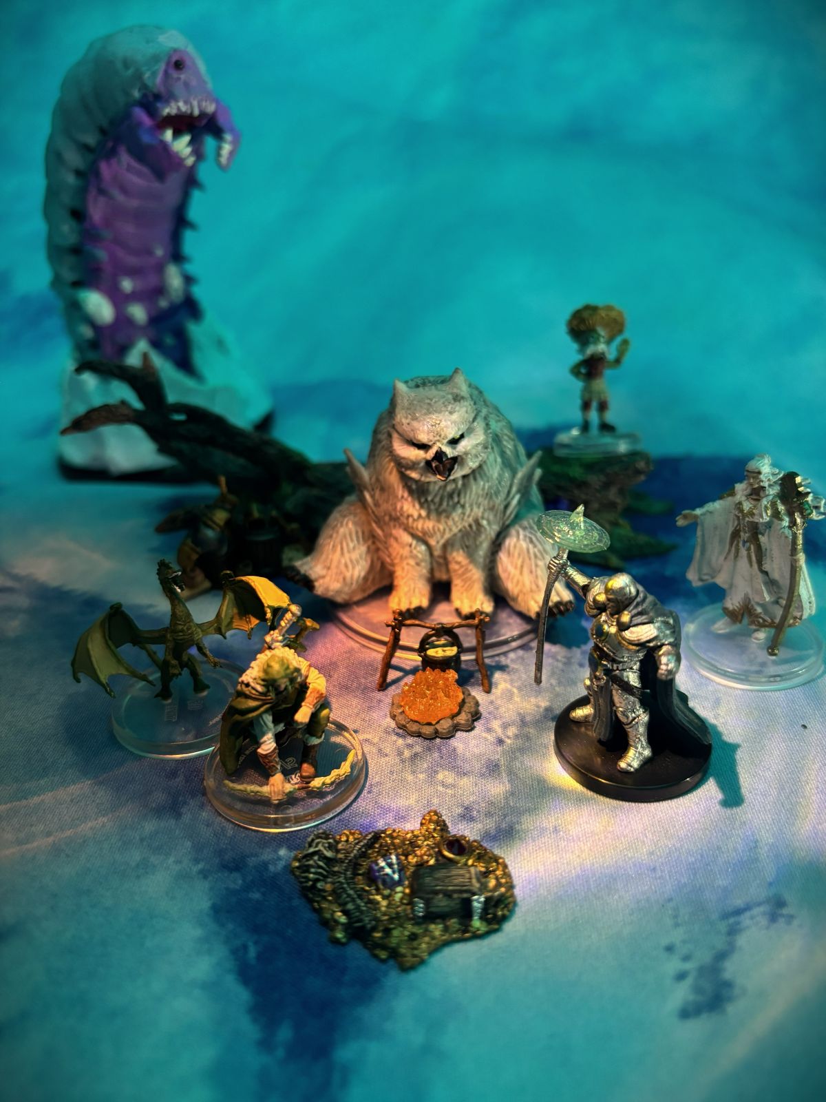 A real tabletop setup with colourful hero miniatures defending modular coastal terrain from a dragon